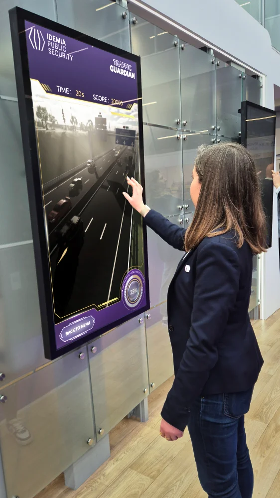 Une visiteuse joue à Traffic Guardian sur la borne tactile IDEMIA